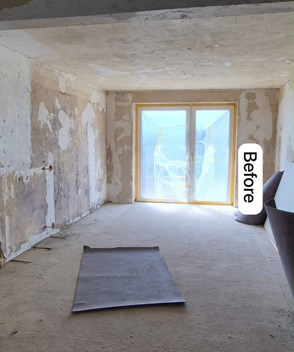 Living room before — bare walls, exposed ceiling and unfinished floor